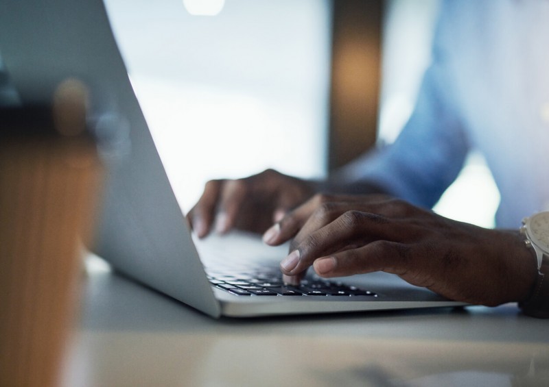 A close up of a man typing on his laptop