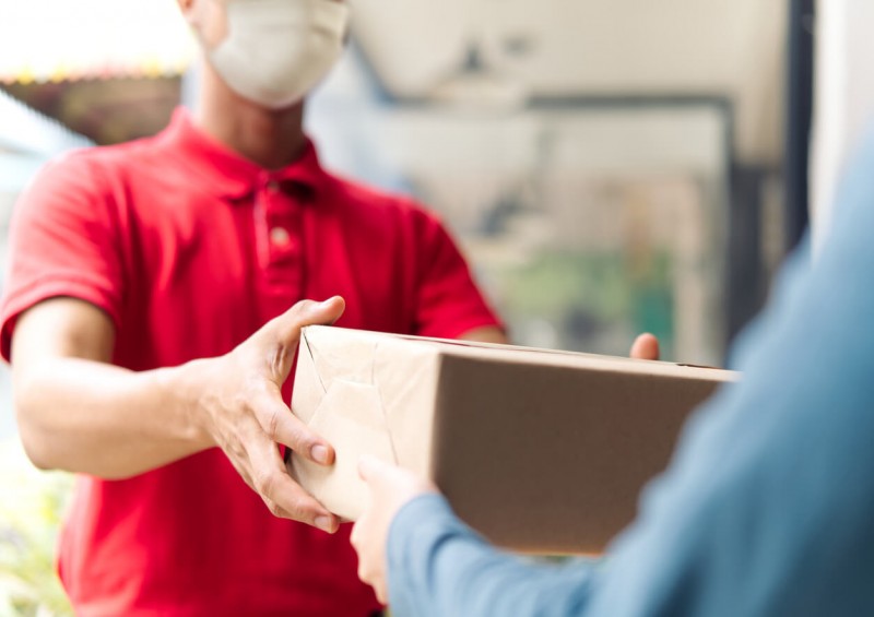 A delivery man wearing a face mask and handing over parcel