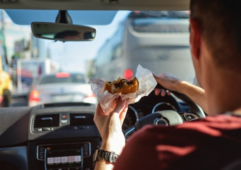 A driver eating a burger while driving