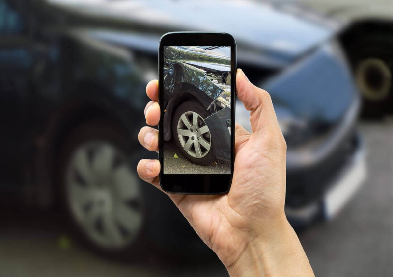A driver taking a photo of his damaged car