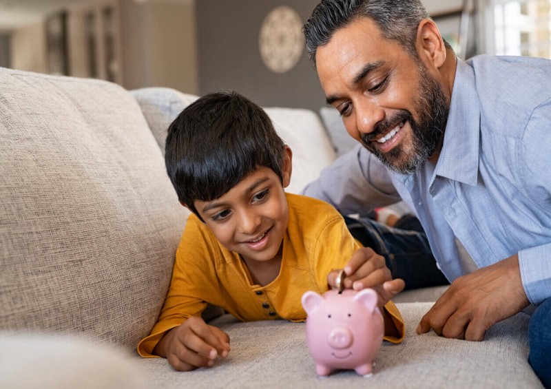 A father teaching his son about money with piggy bank