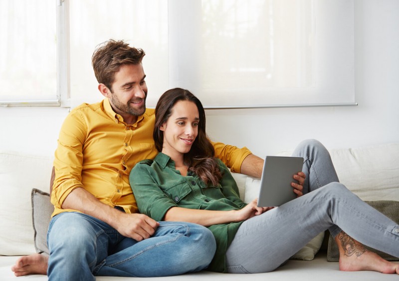 A happy couple sat together looking on their ipad