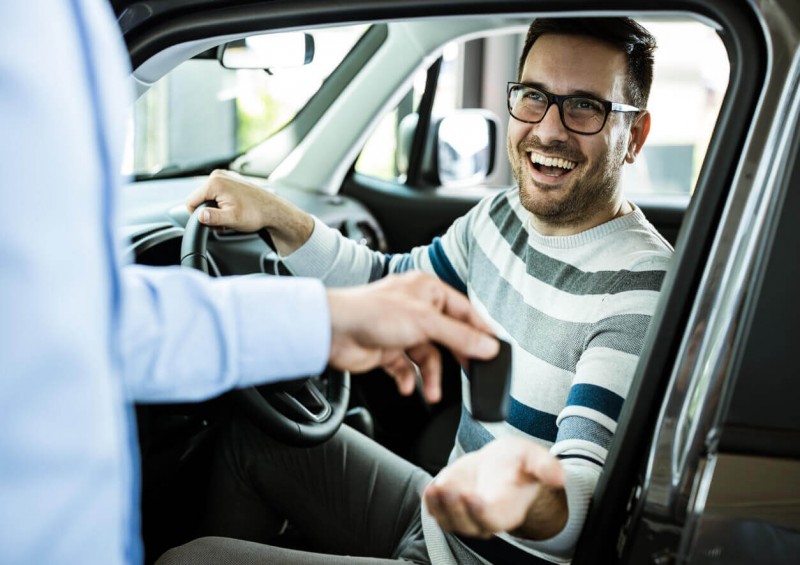 A happy man getting handed the keys to his new car