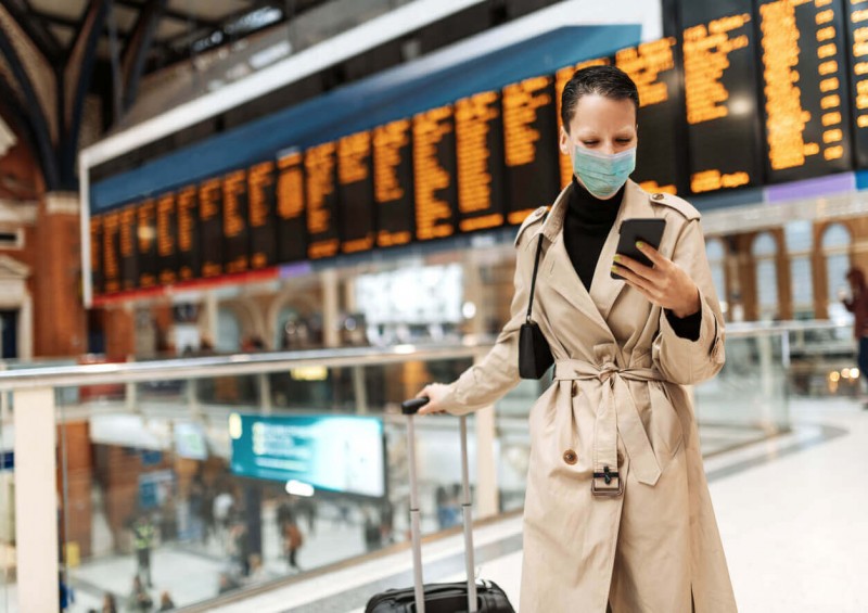 A lady in the airport wearing a mask and checking her phone