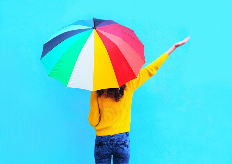 A lady standing under a brightly coloured umbrella