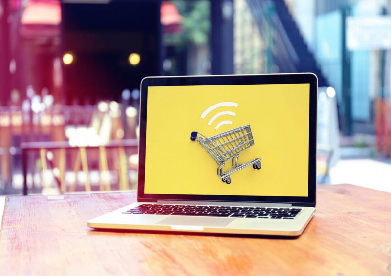 A laptop on a table with a shopping trolley displayed on the screen
