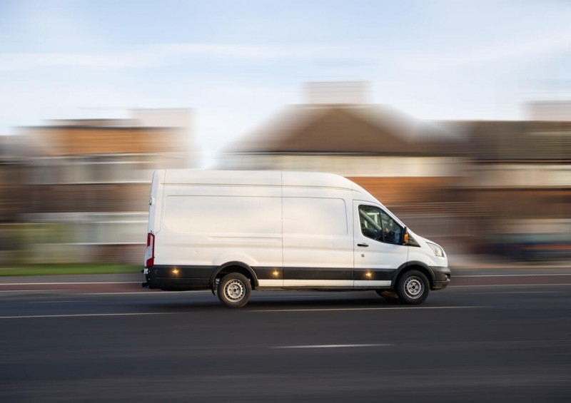 A large white van driving past British houses