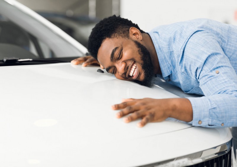 A man hugging the bonnet of his new car