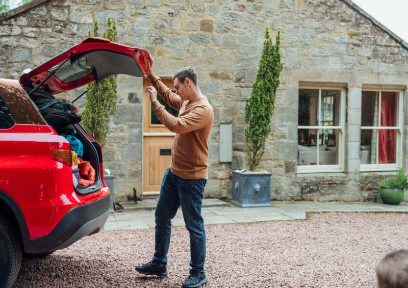 A man looking inside his car outside his home