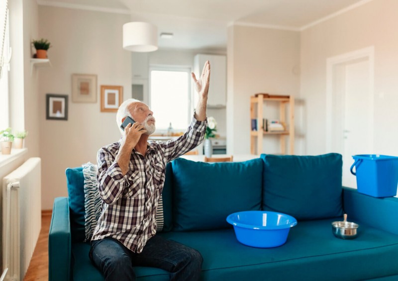 A man on the phone while looking at a leak at home