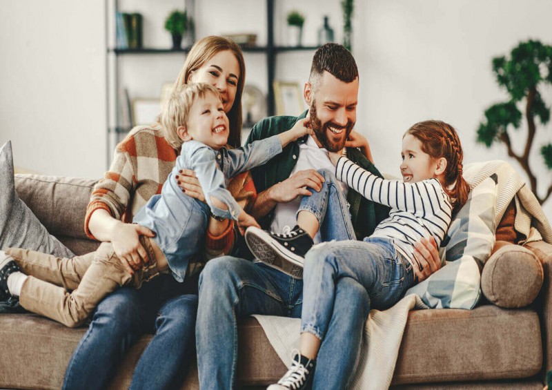 A mother and father laughing with their two children