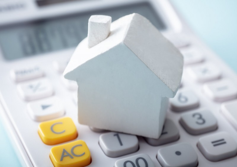 A small white toy house on top of a calculator