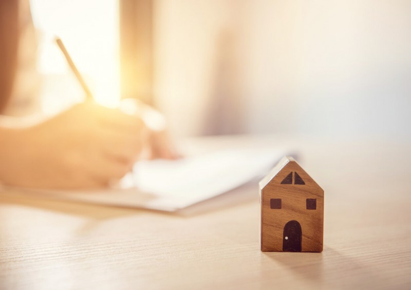 A small wooden house next to someone writing on paper
