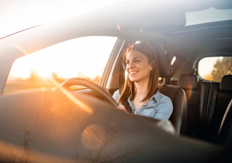 A woman driving her car while smiling