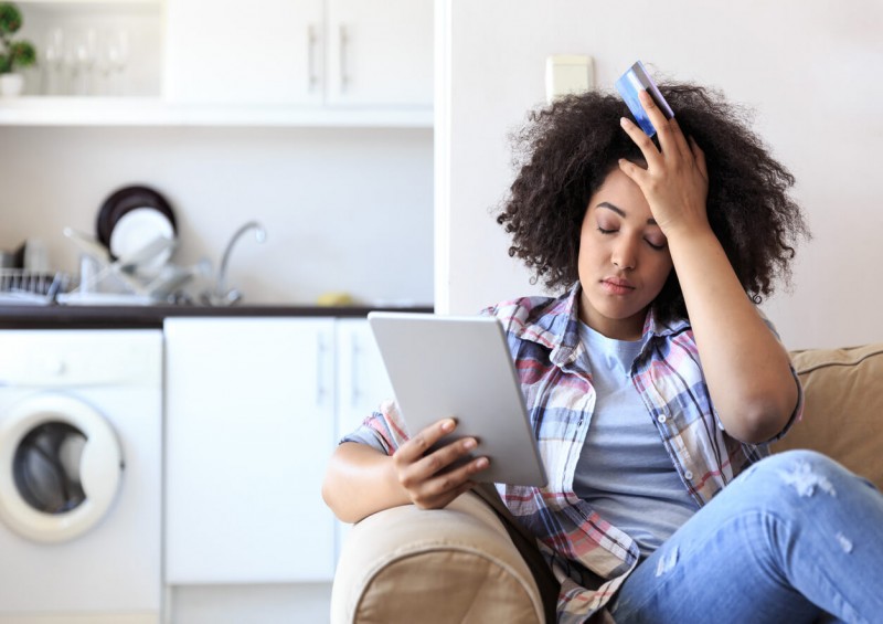 A woman looking frustrated while holding credit card