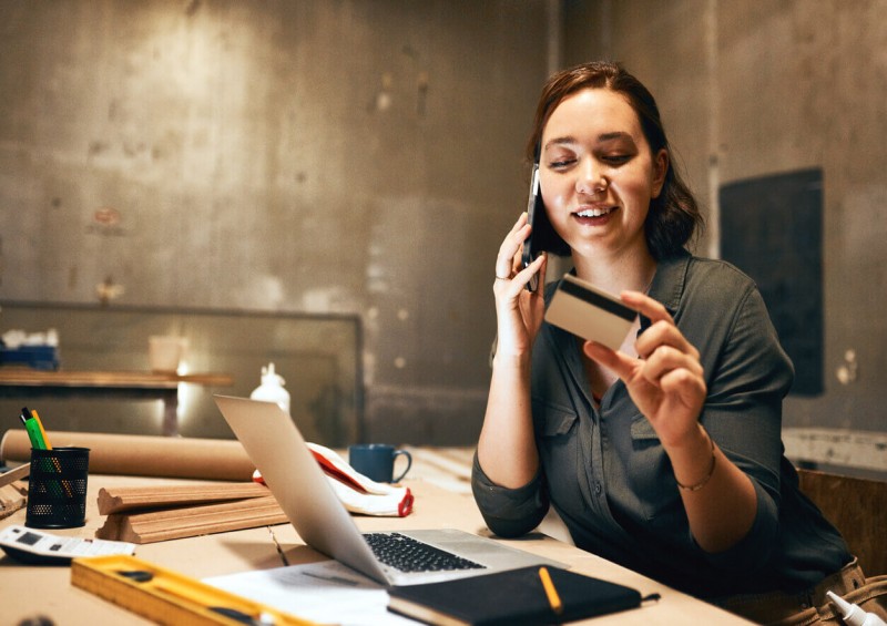 A woman on the phone and looking at her bank card