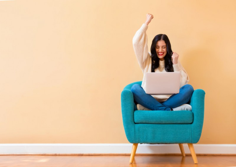 A woman showing gesture of success while on lapton
