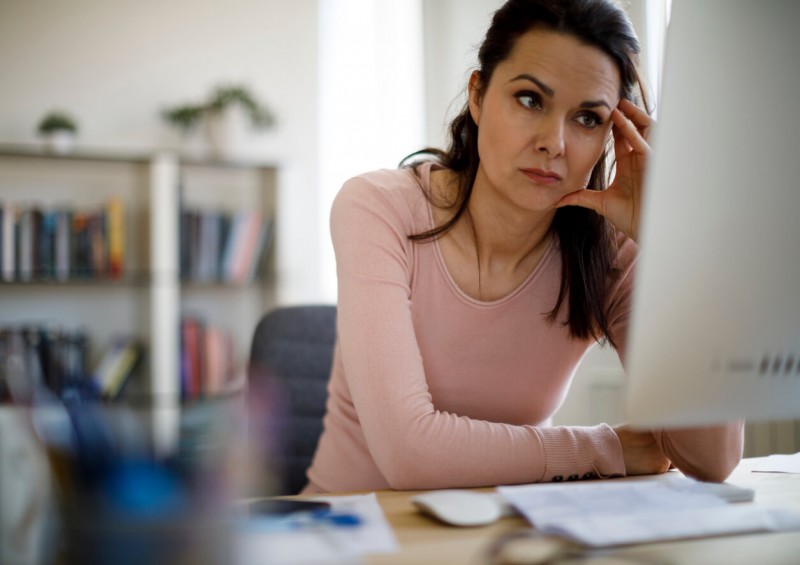 A worried woman looking at her computer screen