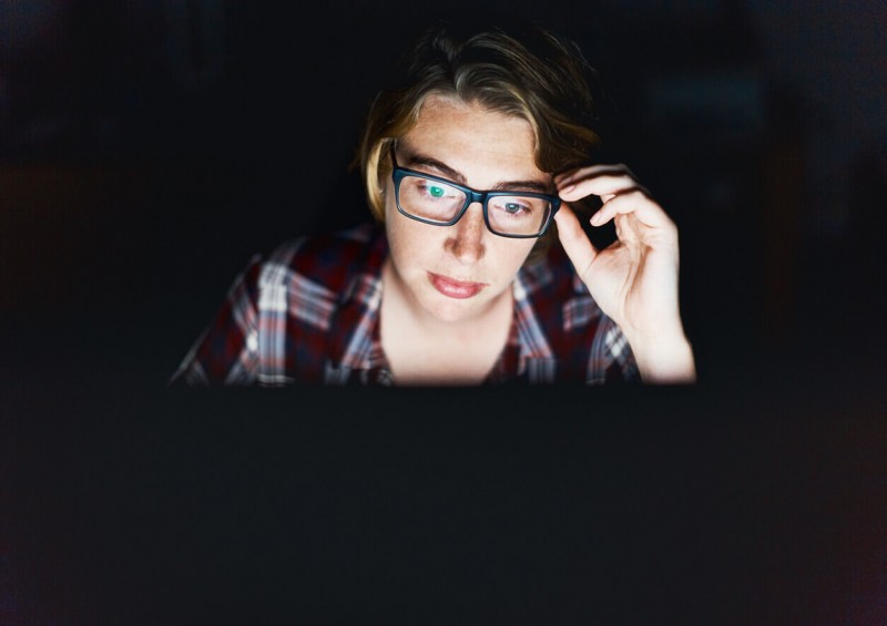 A young woman looking at her laptop in the dark