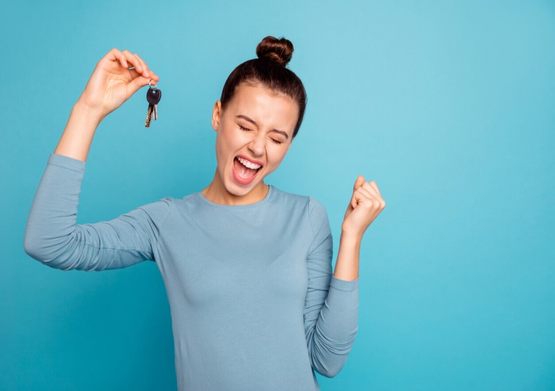 A young woman looking happy holding her new house keys