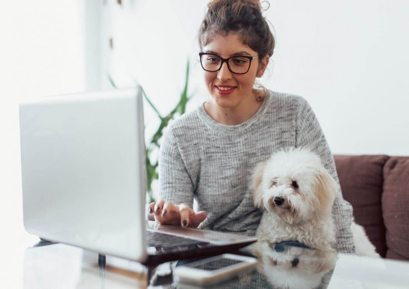 A young woman smiling and looking on her laptop