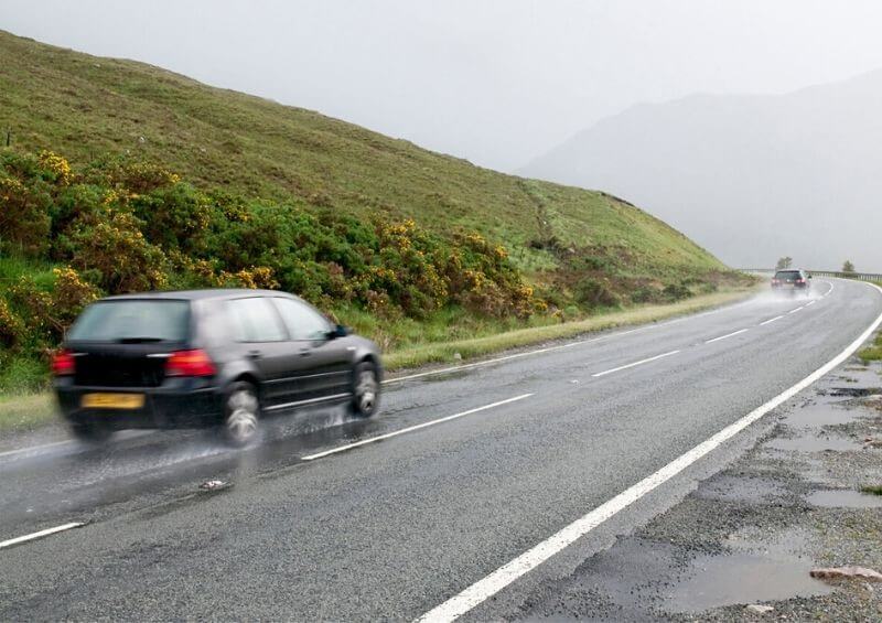 Car driving in rain on a country road