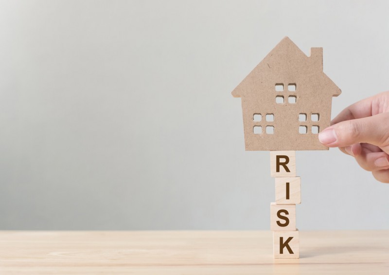 Cardboard cut out of house on top of the word risk