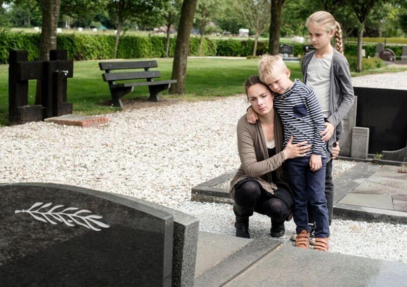 Children and mum visiting grave of their father