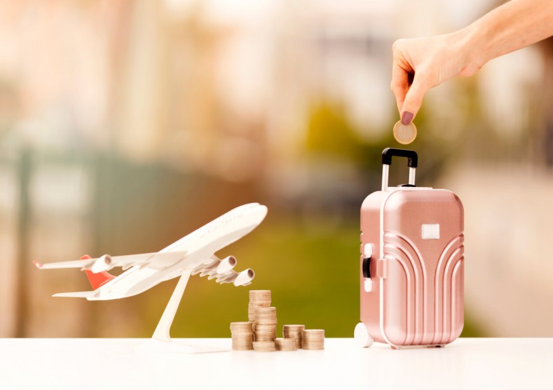 Coins and toy airplane and suitcase