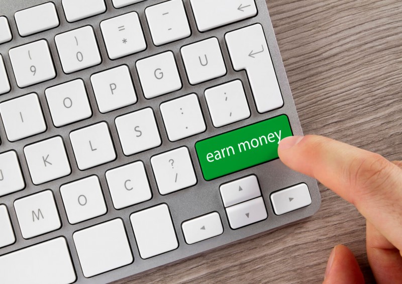 Computer keyboard with green button saying earn money