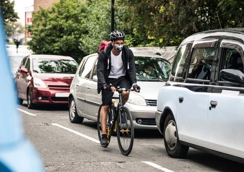 Cyclist driving through cars with mask on