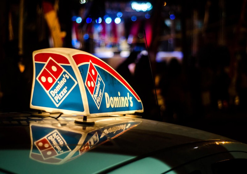 Dominos food delivery car with sign on its roof
