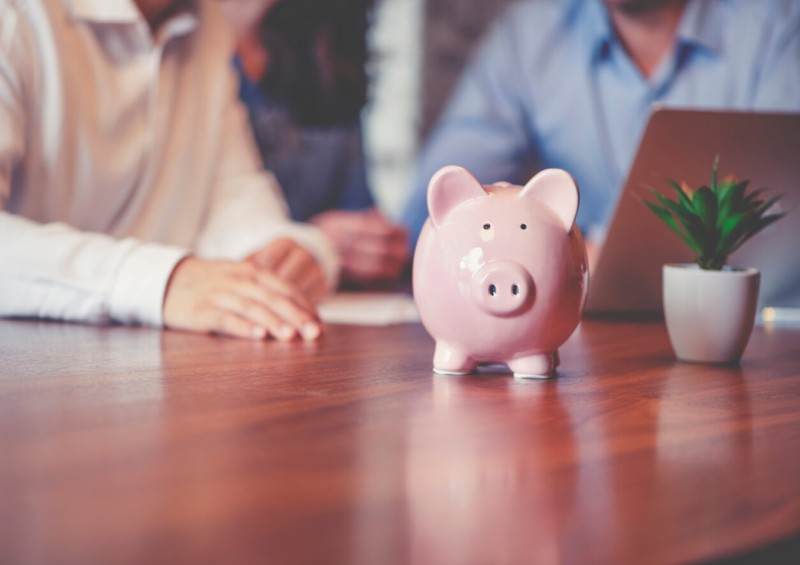 Family sorting finances on laptop next to money box