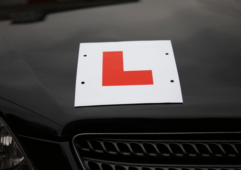 L learner plate on bonnet of black car