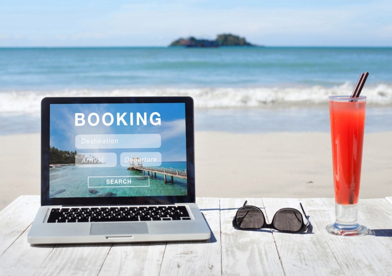 Laptop next to sunglasses and drink on the beach