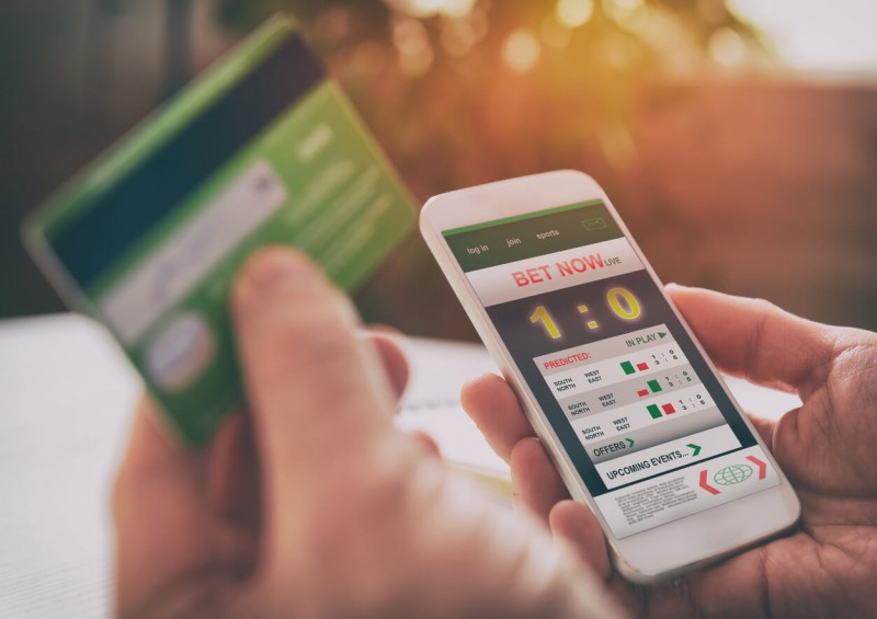 Man gambling online using a smartphone and credit card