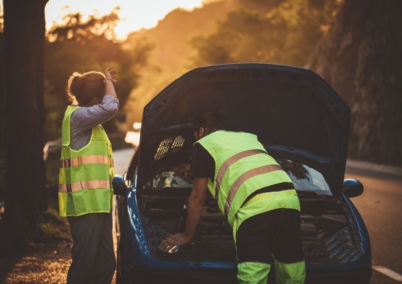 Man helping woman fix car on side of the road