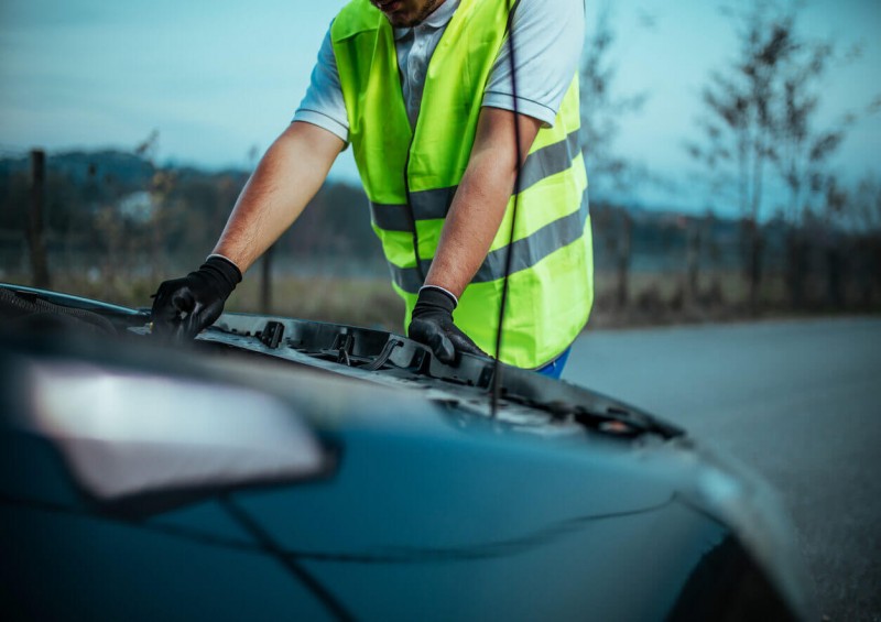 Man in high vis jacket checking car engine