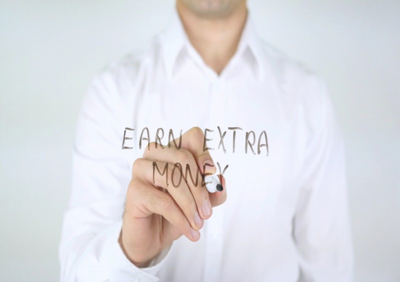Man writing the words earn extra money on glass