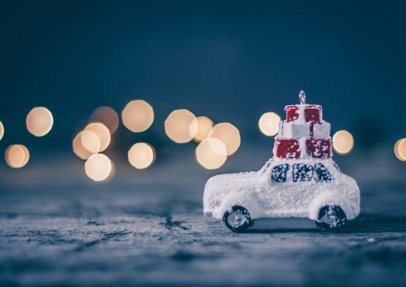 Mini car covered in snow carrying Christmas gifts