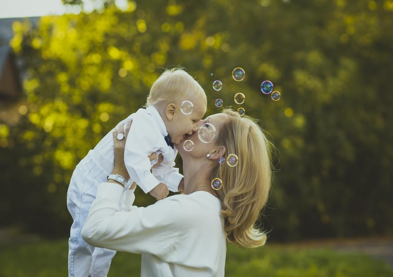 Mother holding up her young child in the garden