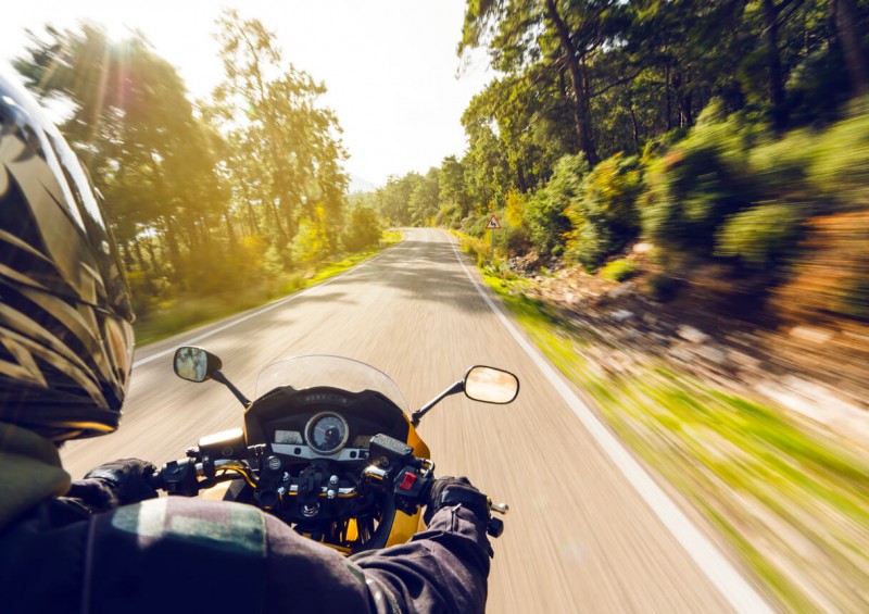 Motorbike going through trees on road