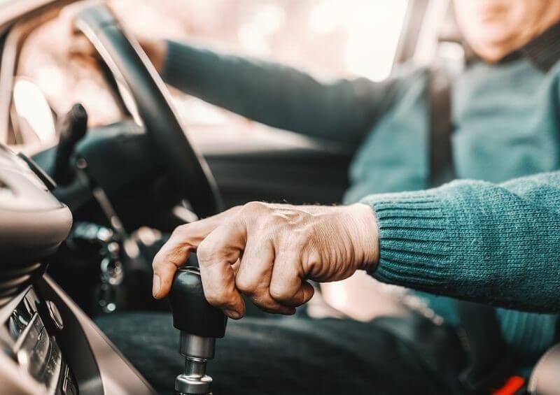 Older gentleman driving car holding gear stick