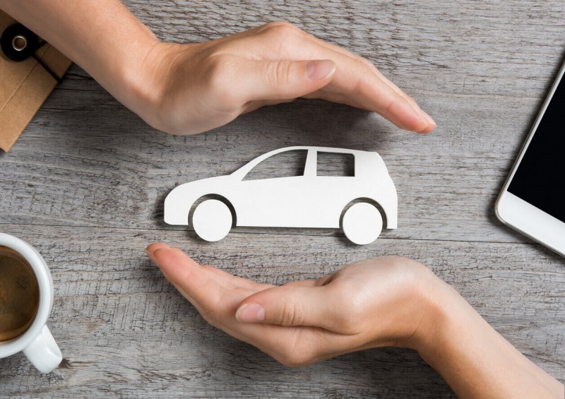 Paper car being protected by two hands