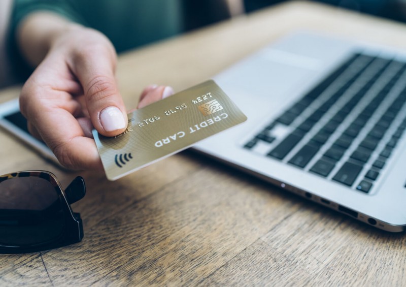 Person holding credit card by laptop