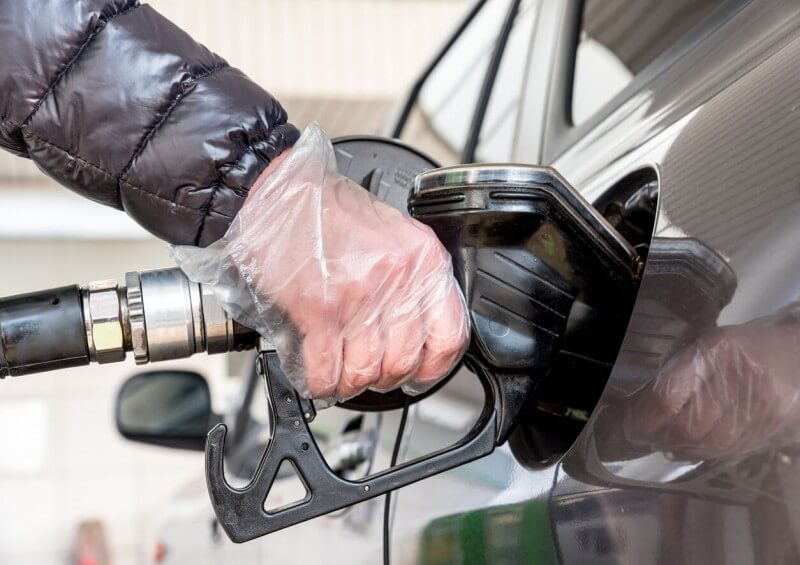 Person putting fuel in car with safety glove on