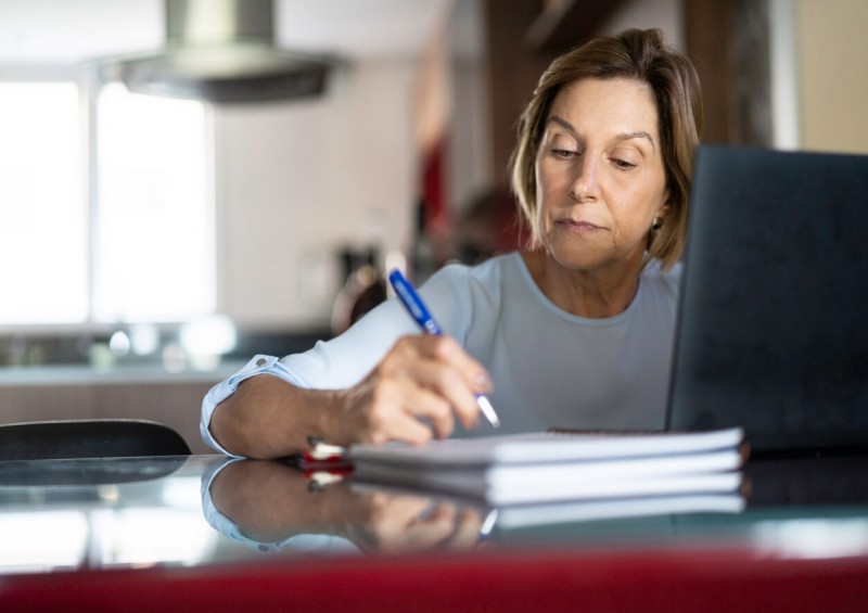 Person signing legal documents by a laptop