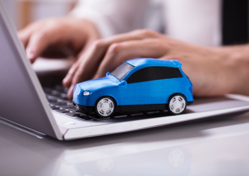 Person typing laptop with car