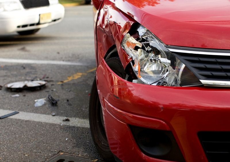Red car with broken headlight after accident