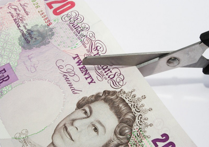 Scissors cutting twenty pound note